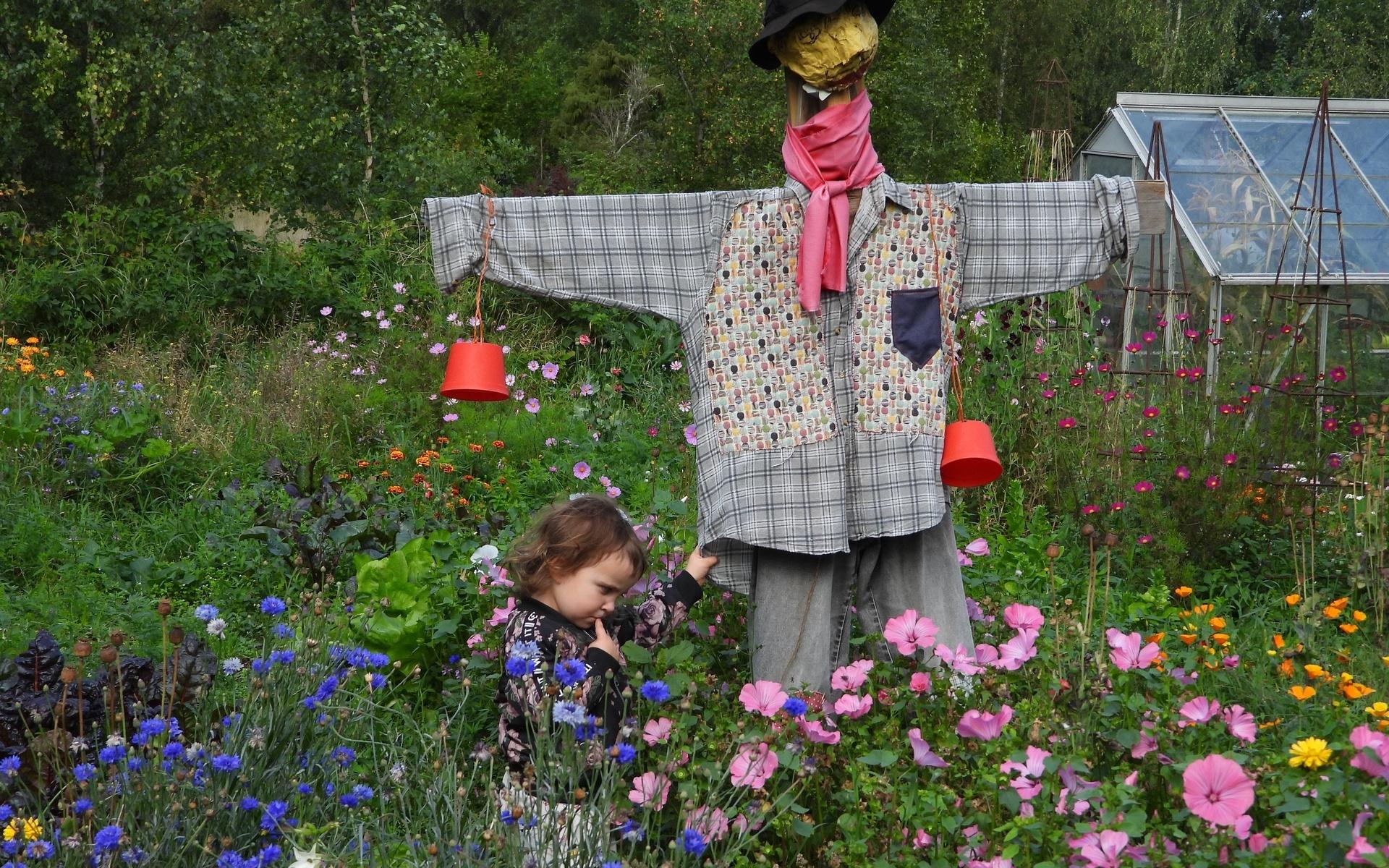 Barnbarnet Saga njuter i Gammelmosters Rosas och Willys trädgård i Dösebacka.  Hon luktade på solen och sa hej till Herr Fågelskrämma. Bild: Beatrice Moberg 