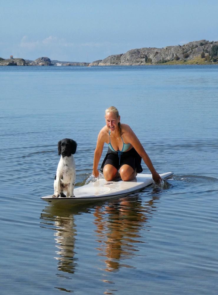 Maria och Unix, 16 veckor, provar att  paddla windsurfingbräda på den spegelblanka Ryskärsfjorden den 22 augusti. Foto: Gunhild Johansen