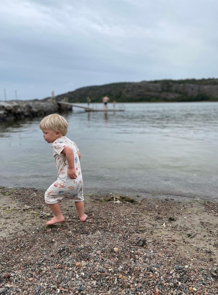 Syskonen badar medan pyjamasklädda Aron jagar efter stenar att kasta i vattnet en kväll vid Lökebergs strand 24 augusti 2021. Foto: Elisabeth Löndahl