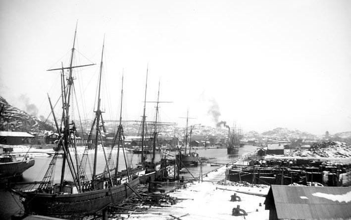 Ett tunt lager nysnö ligger på kajen i Uddevalla denna marsdag år 1898. Bilden är tagen mitt på dagen. Fotografen har stått på Lövåsberget. 
